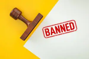 A stamp marked 'BANNED' on a white sheet with a wooden handle stamp.