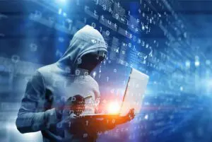 Hacker in a hoodie using a laptop amid digital code.