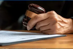 A judge's hand holding a gavel over a document on a desk.