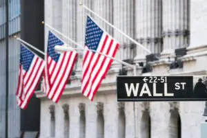 American flags waving near Wall Street sign in New York City.