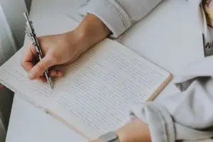 Hand writing notes in a notebook with a pen.