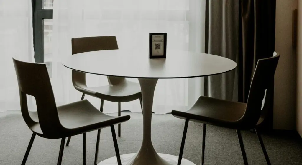 Minimalist round table with two chairs in a softly lit room.