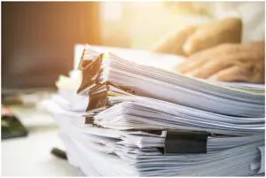 Stack of messy, unorganized paperwork with metal clips.