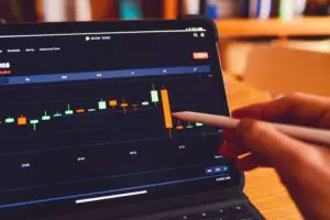 Person pointing at a stock market chart on a tablet.