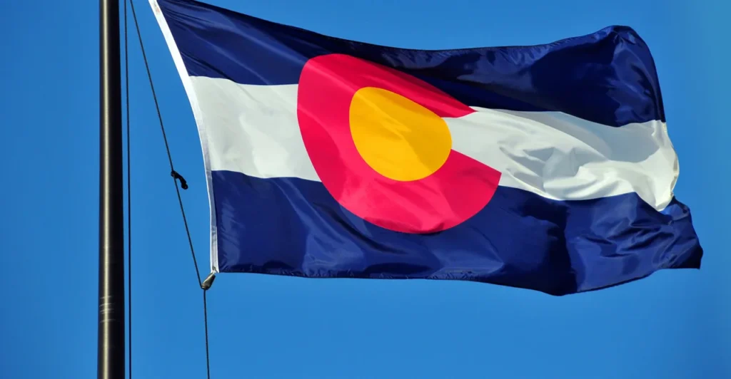 Colorado state flag waving against a clear blue sky.