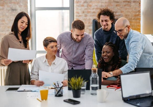 Team collaborating over documents and laptop.